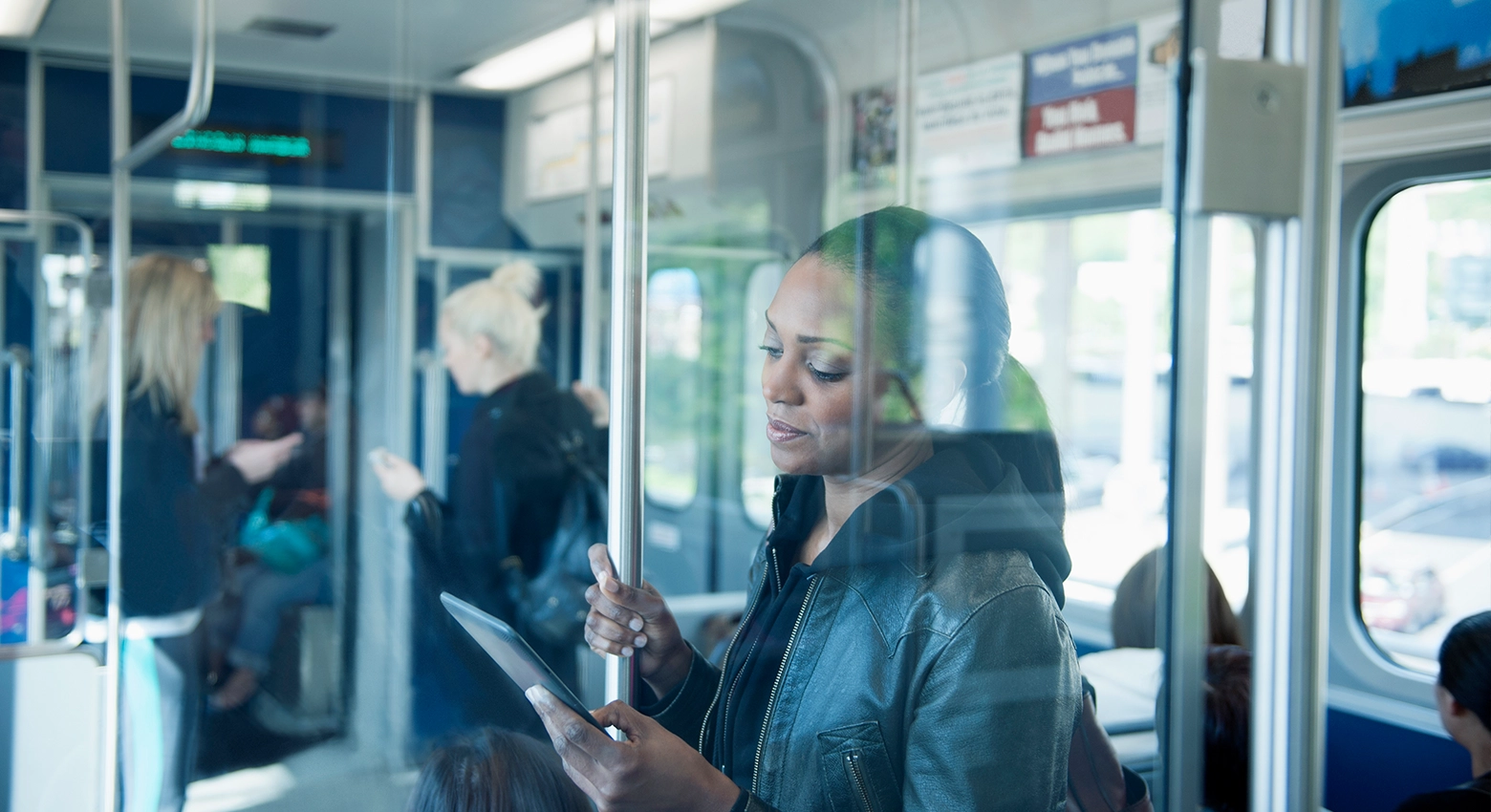 電車の中でタブレットを読む女性 